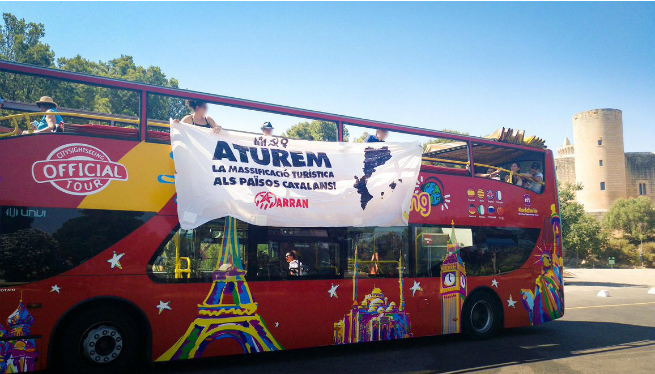 Arran penja una pancarta contra la massificació en un autobús turístic de Palma
