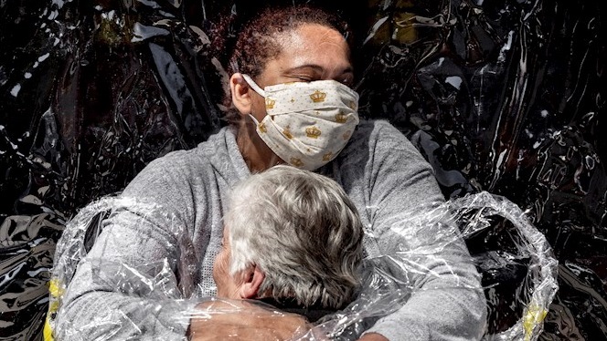 La primera aferrada d’una anciana amb una infermera i entre plàstics de protecció guanya el World Press Photo 2021