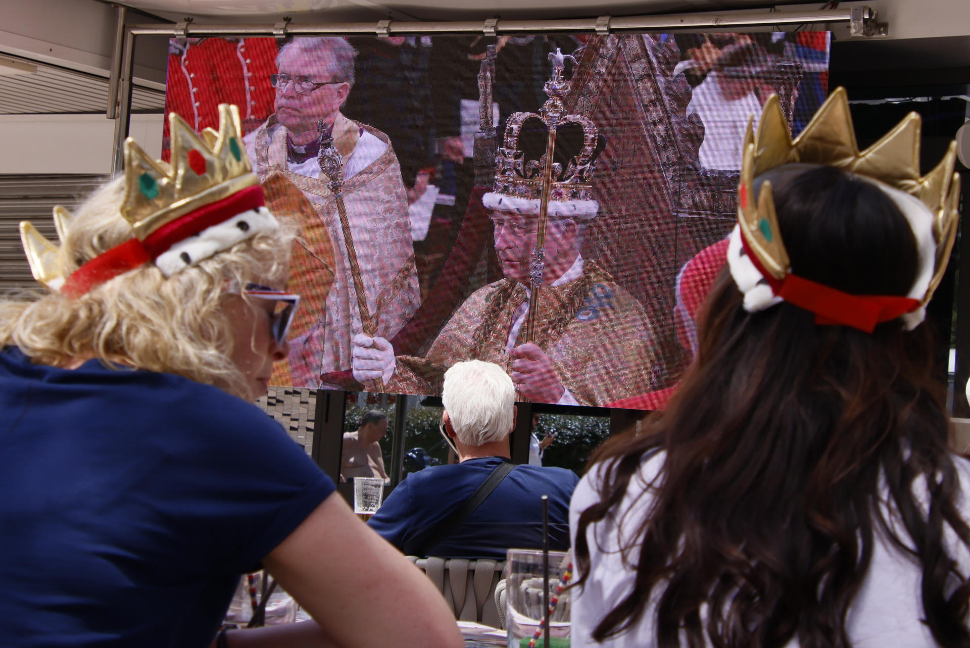 Un grup de turistes britànics dissabte passat a Magaluf seguint en directe la coronació del rei Carles III, amb corones de joguina al cap. EFE/CATI CLADERA